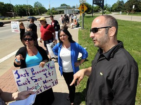 Parents Donna and Anthony Aquino are joined by their lawyer Daniela Cervini (centre) during a protest in front of Assumption High School in Windsor on Monday, June 3, 2013. The parents were protesting what they called unfair treatment of their son Anthony by school officials and classmates. They are suing the both local school boards.           (TYLER BROWNBRIDGE/The Windsor Star)