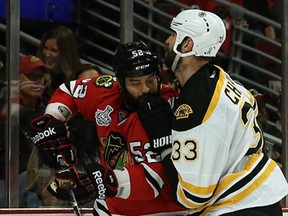 Boston's Zdeno Chara, right, checks Chicago's  Brandon Bollig in Game 1 of the Stanley Cup Final  June 12, 2013 in Chicago. (Bruce Bennett/Getty Images)