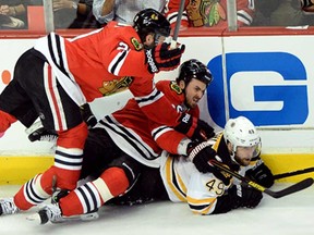 Chicago's Brandon Saad, left, and Dave Bolland fall on top of Boston's Rich Peverley in Game 1 of the Stanley Cup Final at United Center on June 12, 2013 in Chicago. (Harry How/Getty Images)