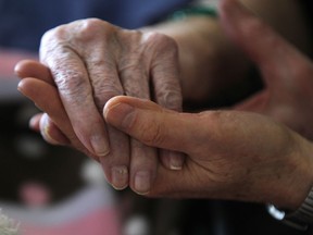 A daughter holds her mother's hand at a long-term care home in Windsor in this 2011 file photo. (JASON KRYK/The Windsor Star)