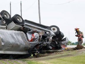 A firefighter with the Kingsville Fire Department inspects an overturned tanker carrying 28 per cent liquid fertilizer on Essex County Road 27, south of Highway 3 in Kingsville, Saturday, June 8, 2013.   (DAX MELMER/The Windsor Star)