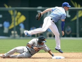 Kansas City's Elliot Johnson, right, leaps over Detroit's Ramon Santiago as he throws to first to complete a double play in the third inning at Kauffman Stadium on June 12, 2013 in Kansas City, Missouri. (Photo by Ed Zurga/Getty Images)