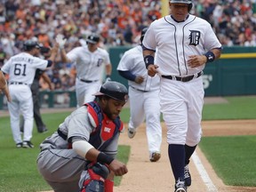 Cleveland catcher Carlos Santana, left foreground, reaches for his mask as Detroit's Miguel Cabrera heads home after Don Kelly's three-run home run in Detroit, Sunday, June 9, 2013. (AP Photo/Carlos Osorio)