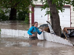 (A woman wades through the flood waters in High River, Alta. on June 20, 2013 after the Highwood River overflowed its banks. (THE CANADIAN PRESS/Jordan Verlage)