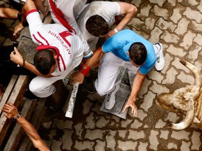 Revellers run by a fallen Fuente Ymbro ranch fighting bull during the running of the bulls of the San Fermin festival, in Pamplona, Spain, Saturday, July 13, 2013. Revellers from around the world arrive in Pamplona every year to take part in eight days of the running of the bulls glorified by Ernest Hemingway's 1926 novel 'The Sun Also Rises.' (Daniel Ochoa de Olza/Associated Press)