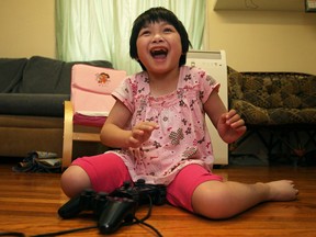 Alleni Lu, 6, who has cerebral palsy, sits on the floor of her living room, Saturday, July 27, 2013.  The Lu family has been awarded free insulation through a give-away contest from Great Northern Insulation.   (DAX MELMER/The Windsor Star)