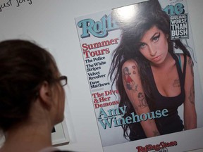 A woman looks at a poster-sized print of the cover of Rolling Stone magazine featuring a picture of British singer Amy Winehouse displayed at the "Amy Winehouse A Family Portrait" exhibition at the Jewish Museum in North London on July 2, 2013.  It is Amy Winehouse, but not as we know her. The mass of dark hair, steady gaze and full lips are instantly recognizable, but there is no hint of the scrawny, tattoed addict she would later become. Intimate family photographs, displayed for the first time in a new exhibition which opened July 3, offer a heartbreaking glimpse of the fresh-faced Jewish girl who grew up to become one of Britain most famous soul singers. (ANDREW COWIE/AFP/Getty Image)