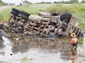 Crews work to pull a semi truck out of a pond after a collision that left a small car submerged in the water on Saturday, July 27, 2013. Six teens died in the submerged car. (JASON FRANSON , THE CANADIAN PRESS)