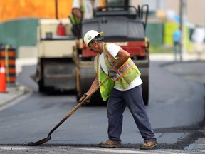 An employee with Coco Paving works on a hot morning, Monday, July 15, 2013, in downtown Windsor, Ont. A crew was repaving a section of road on Church Street near University Avenue. (DAN JANISSE/The Windsor Star)