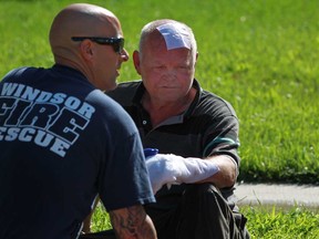 The resident of 1366 Central Ave. is tended to by a Windsor firefighter for burns to his hand and head which he sustained after his boat caught fire and spread to his home, Thursday, July 11, 2013.  The fire also spread to a home next door.  (DAX MELMER/The Windsor Star)