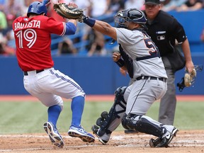 Toronto's Jose Bautista, left, scores a run in the third inning as Detroit's Brayan Pena cannot handle the throw Monday at Rogers Centre in Toronto, (Photo by Tom Szczerbowski/Getty Images)