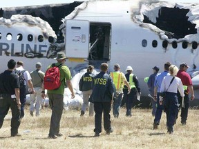 This handout photo provided July 7, 2013 by the National Transportation Safety Board, shows an NTSB investigative team arriving to inspect the wreckage of Asiana Flight 214 during their first site assessment in San Francisco. U.S. officials were combing through the wreckage of an Asiana Airlines Boeing 777 passenger jet in San Francisco Sunday, as they tried to determine why it crashed onto the runway July 6, killing two people and injuring 182 others. The crash sheared off the plane's landing gear and tore the tail off the fuselage. Large portions of the plane's body were burned out in the fire that then erupted. But National Transportation Safety Board chief Deborah Hersman said much of the destruction isn't visible in the pictures and footage shown in the news.  (AFP PHOTO/ HANDOUT / NTSB)