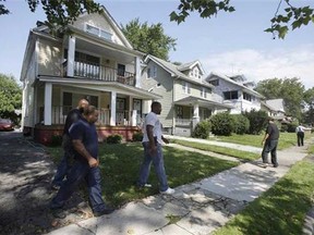 East Cleveland police officers search a neighborhood Sunday, July 21, 2013, near where three bodies were recently found, in East Cleveland, Ohio. The bodies, believed to be female, were found about 100 to 200 yards (90 to 180 metres) apart, and a 35-year-old man was arrested and is a suspect in all three deaths, though he has not yet been charged, East Cleveland Mayor Gary Norton said Saturday. (AP Photo/Tony Dejak)