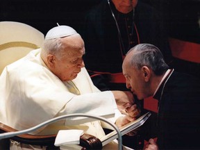 In this undated picture released by Sergio Rubin, Jorge Mario Bergoglio, Archbishop of Buenos Aires, right, kisses the hand of Pope John Paul II during a ceremony at the Vatican. Bergoglio, who became Pope Francis on Wednesday, March 13, 2013, cleared Pope John Paul II for sainthood, approving a miracle attributed to his intercession and setting up a remarkable dual canonization along with another beloved pope, John XXIII. (AP Photo/Sergio Rubin)