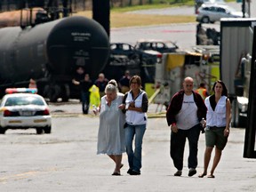 Volunteers escort evacuees to their home near the blast site to pick up some belongings Monday, July 8, 2013 in Lac-Mégantic, Que. after a train derailed igniting tanker cars carrying crude oil. Five people are confirmed dead and 40 more are listed as missing. (THE CANADIAN PRESS/Ryan Remiorz)