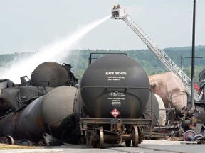 Fire fighters keep watering railway cars the day after a train derailed causing explosions of railway cars carrying crude oil Sunday, July 7, 2013, in Lac Megantic, Que. (THE CANADIAN PRESS/Paul Chiasson)
