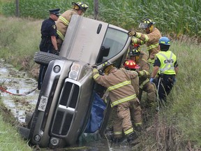 Emergency personnel work to rescue a man trapped in a truck Wednesday, July 31, 2013, in a ditch on Holden Road in Tecumseh, Ont. The accident occurred around 11 a.m. and after being extricated the man walked away uninjured.  (DAN JANISSE/The Windsor Star)