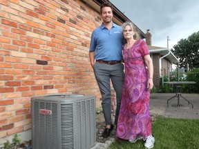 Rosemary Robinson (R) stands with Tom Scully of Fahrhall Home Comfort Specialists by Robinson's brand new air conditioning unit - provided and installed by the company for free. Photographed July 18, 2013. (Dan Janisse / The Windsor Star)