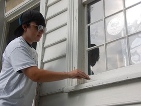 St. Joseph high school student Mark Pajot, 14, scrapes a window frame on July 31, 2013, at the Park House Museum in Amherstburg. (Julie Kotsis/The Windsor Star)