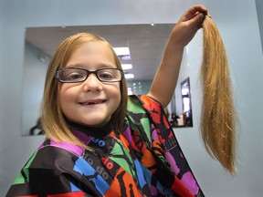 Alexia Bilodeau, 5, got her long blonde hair cut Friday, July 19, 2013, in Kingsville, Ont. and will donate it to an organization that makes wigs for cancer patients. She proudly shows her freshly chopped pony tail. (DAN JANISSE/The Windsor Star)