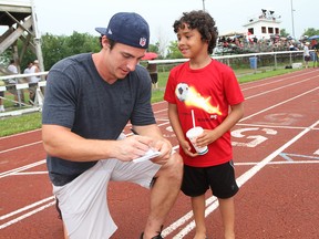 LaSalle's Luke Willson, 23, who was recently drafted by the Seattle Seahawks, signs an autograph for fan Darrius Gerard, 7, before the Essex Ravens game at Raider Field in Essex on Saturday, July 6, 2013. (REBECCA WRIGHT/
