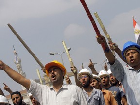 Supporters of Egypt's Islamist President Mohammed Morsi hold sticks and wear protective gear outside of the Rabia el-Adawiya mosque near the presidential palace, in Cairo, Egypt, Tuesday, July 2, 2013. (AP Photo/Amr Nabil)