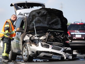 A Windsor firefighter inspects a vehicle that caught fire after colliding with another vehicle at the intersection of Banwell Road and E.C. Row Expressway, Friday, July 12, 2013.  (DAX MELMER/The Windsor Star)