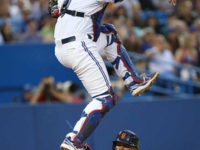 Detroit's Ramon Santiago, right, slides safely in the sixth inning to score a run as Toronto's J.P. Arencibia jumps for the throw on July 4, 2013 at Rogers Centre in Toronto, Ontario, Canada. (Photo by Tom Szczerbowski/Getty Images)