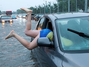 A woman gets back into her flooded car on the Toronto Indy course on Lakeshore Boulevard in Toronto on Monday, July 8 2013. THE CANADIAN PRESS