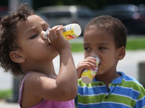 Paytience Crosby-Morgan, 3, and her brother Jayms Crosby-Morgan, 2, cool down with some juice at the Sandpoint Beach, Tuesday, July 9, 2013, in Windsor, Ont. on a sweltering hot day. (DAN JANISSE/The Windsor Star)