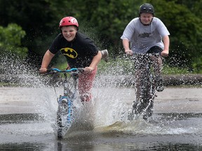 Brandon Defausses, 12, (L) and his buddy Nicholas Shay, 15, blasts through a large puddle of water left over from recent rain at the Malden Park in Windsor, Ont. on Tuesday, July 2, 2013. (DAN JANISSE/The Windsor Star)