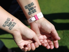 Connie Burgess and her daughter, Cortnee Burgess, left, hold out their matching tattoos, Saturday, August 24, 2013, commemorating Dennis Burgess, Cortnee's father and Connie's husband, who died in 2011.  (DAX MELMER/The Windsor Star)