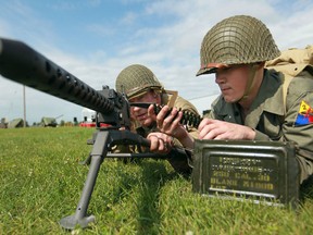 Mike Handfield, left, and Stefan Pahapill, both dressed in Second World War military uniforms, man a Browning M-1919 A4 at the Military Muster at Essex Memorial Arena, Saturday, August 10, 2013.  (DAX MELMER/The Windsor Star)