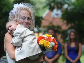 Christine Swidorsky carries her son and the couple's best man, Logan Stevenson, 2, down the aisle to her husband-to-be Sean Stevenson during the wedding ceremony on Saturday, Aug. 3, 2013 in Jeannette, Pa. Logan stood with his grandmother, Debbie Stevenson, during a 12-minute ceremony uniting Logan's mother and his father. The boy has leukemia and other complications. The Stevensons abandoned an original wedding date of July 2014 after learning from doctors late last month that their son had two to three weeks to live. The couple wanted Logan to see them marry and to be part of family photos. Logan, who was born Oct. 22, 2010, was diagnosed shortly after his first birthday with acute myeloid leukemia. He has Fanconi anemia, a rare disease that often leads to cancer. (AP Photo/Tribune Review, Eric Schmadel)