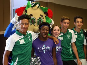 Members of ICG team from Graz, Austria arrive at Windsor Airport where they were greeted by cheerleaders and food and drinks from Subway August 13, 2013. Austria team member Lauris Ochaya, left, poses with North Star Cheer cheerleaders Neely Ducre and Cassandra Coates along with Austrian teammates Tobias Haboch and Manual Albinger, right, at Windsor Airport.  Behind Subway mascot, James Summerfield was popular with the the athletes and coaches.  (NICK BRANCACCIO-The Windsor Star)