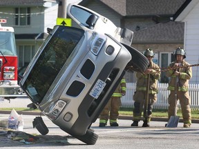 Tecumseh firefighters watch as a vehicle involved in a collision Thursday, Aug. 1, 2013, at Lesperance Road and Arbour Street in Tecumseh, Ont.. is upended. The accident occurred shortly after 9 a.m. between a Ford Lincoln and a Pontiac Montana minivan. No one was injured. (DAN JANISSE/The Windsor Star)