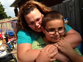 Jacqueline Baston, left, hopes to recover or replace the tricycle missing from her backyard, August 20, 2013.  The Snoop Dogg Trike was used by her son, Aidan Baston-Firr, 10, right.  The family resides on Raymo Avenue in Windsor, Ont.  (NICK BRANCACCIO/The Windsor Star)