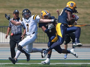 University of Windsor's defensive back, Mike Dubuisson, intercepts a pass intended for Waterloo's Nick Anapolsky, left, while Windsor's Dave McDuffie, centre, helped with the double coverage during the U of W's football season opener against the Waterloo Warriors at Alumni Field, Sunday, August 25, 2013.  (DAX MELMER/The Windsor Star)