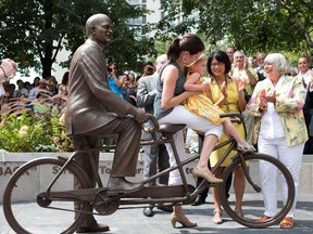 Olivia Chow, centre right, looks on as Sarah Layton and her daughter Beatrice sit on a bronze statue of Jack Layton, the former NDP leader after it's unveiling at Toronto's ferry terminal on Thursday, August 22, 2013. (THE CANADIAN PRESS/Chris Young)