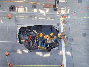 An aerial photograph shows a backhoe which was partly swallowed by a sinkhole earlier in the morning in Montreal on Monday August 05, 2013.A broken sewer pipe may be the cause of the city's latest downtown sinkhole, a city official said Monday morning. "It might be a sewer pipe," Ville-Marie spokesperson Emilie Miskdjian told reporters after part of Ste-Catherine St. W., from St-Mathieu St. to Guy St., was completely blocked off by police Monday morning.The operator of the backhoe was taken to hospital for evaluation, Miskdjian said.(Marie-France Coallier/ THE GAZETTE)