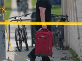 A Windsor police officer walks with the piece of luggage that was the centre of a "suspicious package" call on Wyandotte Street West on August 20, 2013. Social media helped police determine that the luggage was not of a threatening nature.  (JASON KRYK/The Windsor Star)