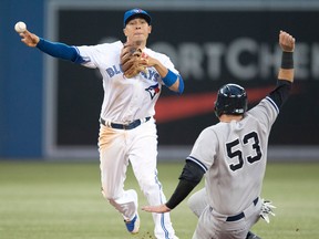 Toronto's Ryan Goins, left, forces out New York's Austin Romine at second base as he turns a double play Monday in Toronto. (THE CANADIAN PRESS/Frank Gunn)