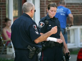 Windsor Police Sgt. Kevin Bleyendaal, left, speaks with an injured officer after a foot pursuit where a suspect was apprehended and arrested after a struggle August 29, 2013. The officer was injured during the struggle and Windsor-Essex EMS paramedics were called to Erie Street East near Pierre Avenue.  The suspect was apprehended a few blocks away. (NICK BRANCACCIO/The Windsor Star)