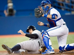 Toronto catcher J.P. Arencibia, right, prepares to throw to second base after tagging out New York's Alex Rodriguez at home plate during the fourth inning in Toronto Wednesday. (THE CANADIAN PRESS/Frank Gunn)