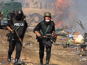 A wounded member of the police is helped by another as Egyptian security forces clear a sit-in by supporters of ousted Islamist President Mohammed Morsi in the eastern Nasr City district of Cairo, Egypt, Wednesday, Aug. 14, 2013. Egyptian security forces, backed by armored cars and bulldozers, moved on Wednesday to clear two sit-in camps by supporters of the country's ousted President Mohammed Morsi, showering protesters with tear gas as the sound of gunfire rang out at both sites. (AP Photo/Ahmed Gomaa)