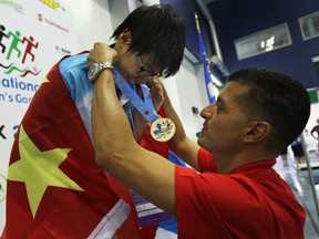 Hou Yushan, left, from Beijing, China, receives the 400m freestyle swimming gold medal from mayor Eddie Francis at the International Children's Games being held at the Windsor International Aquatic and Training Centre,  Friday, August 16, 2013.  (DAX MELMER/The Windsor Star)