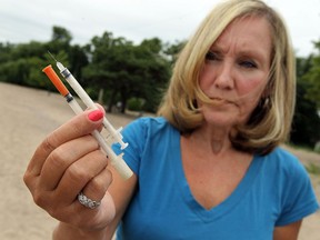 D.J. Meadows is photographed on the Lake Erie beach near her home with a pair of syringes she found on the beach after a storm on Thursday, August 8, 2013. Meadows found a total of 9 needles on the beach and heard more were discovered along the nearby shoreline.          (TYLER BROWNBRIDGE/The Windsor Star)