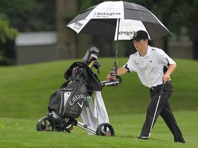 Riley Fry tries to stay dry, Monday, Aug.12, 2013, during the Jamieson Junior Golf Tour event at the Pointe West Golf Club in Amherstburg. (DAN JANISSE/The Windsor Star)