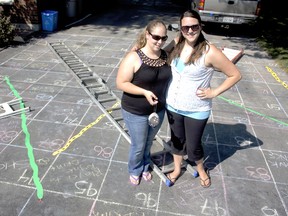 Neighbours Samantha Karpala (left) and Carli Brown stand on their life-sized Snakes and Ladders board game built and designed on their vacant driveway in LaSalle, Sunday, August 25, 2013. (JOEL BOYCE / The Windsor Star)