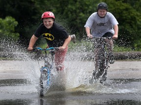 Brandon Defausses, 12, left, and his buddy Nicholas Shay, 15, blasts through a large puddle of water from recent rain at the Malden Park in Windsor on Tuesday, July 2, 2013. (DAN JANISSE/The Windsor Star)